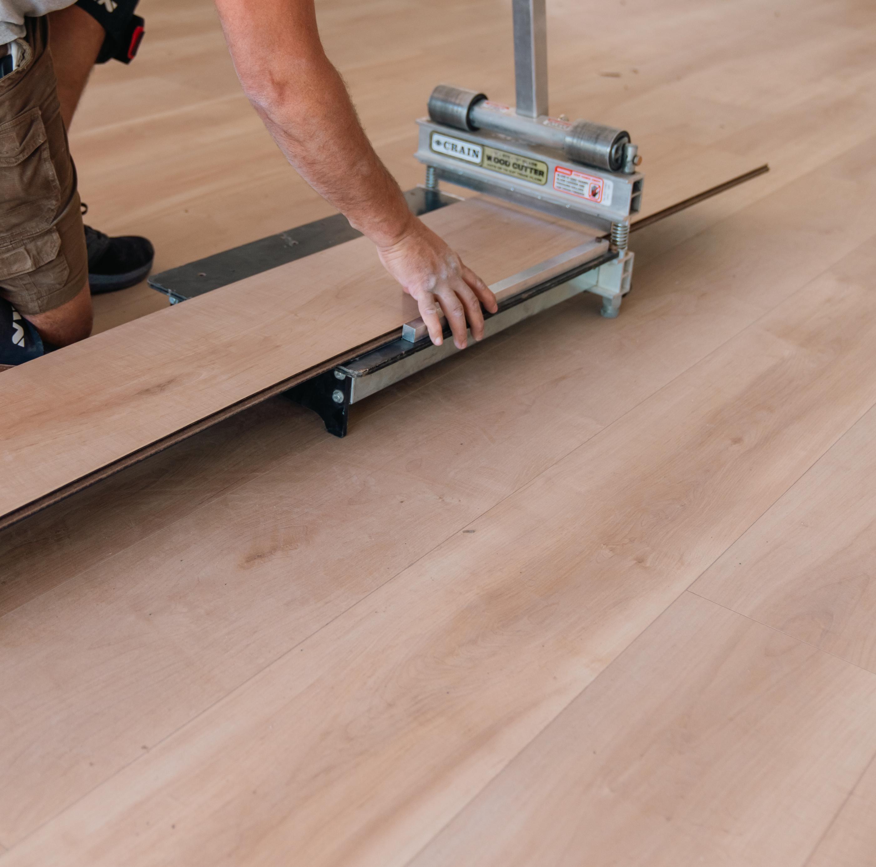 Professional installing laminate flooring with precision tools for seamless finish.
