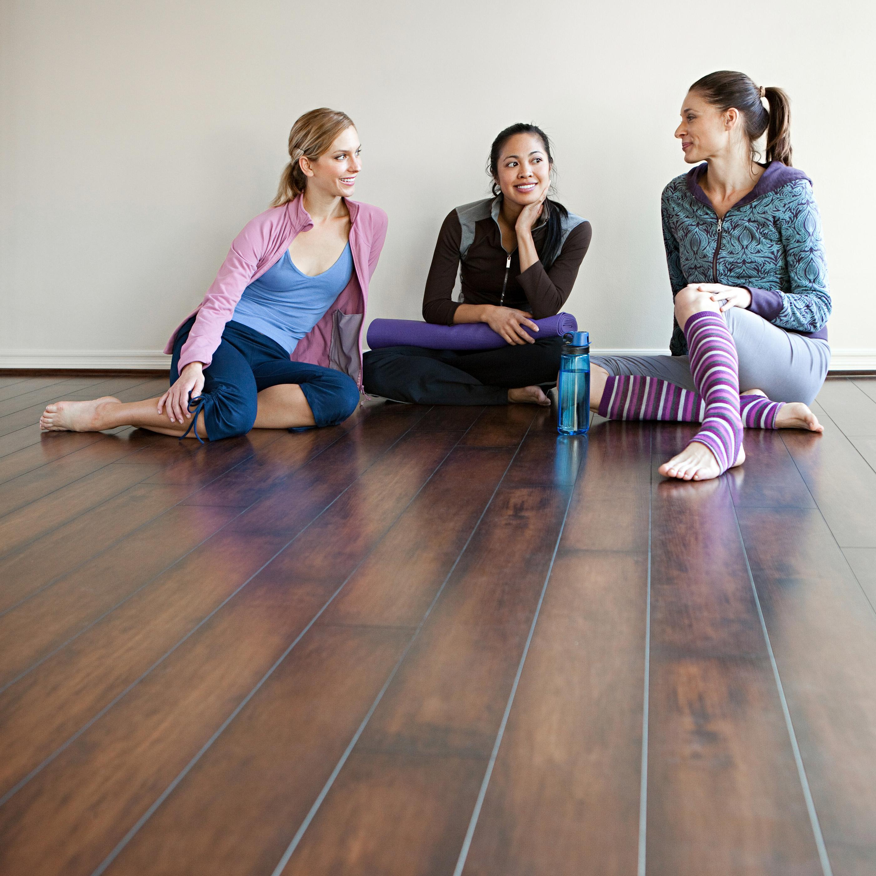 Three women on a laminate floor, sitting together and interacting in a relaxed atmosphere.